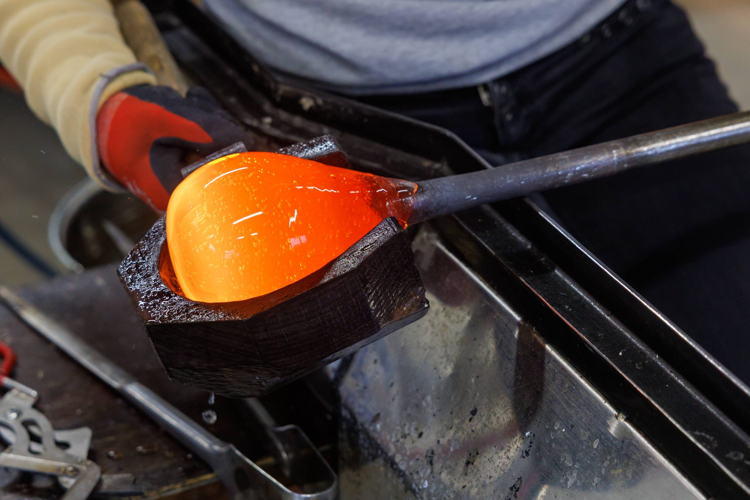 Shaping the glass mass with a wooden block before blowing.