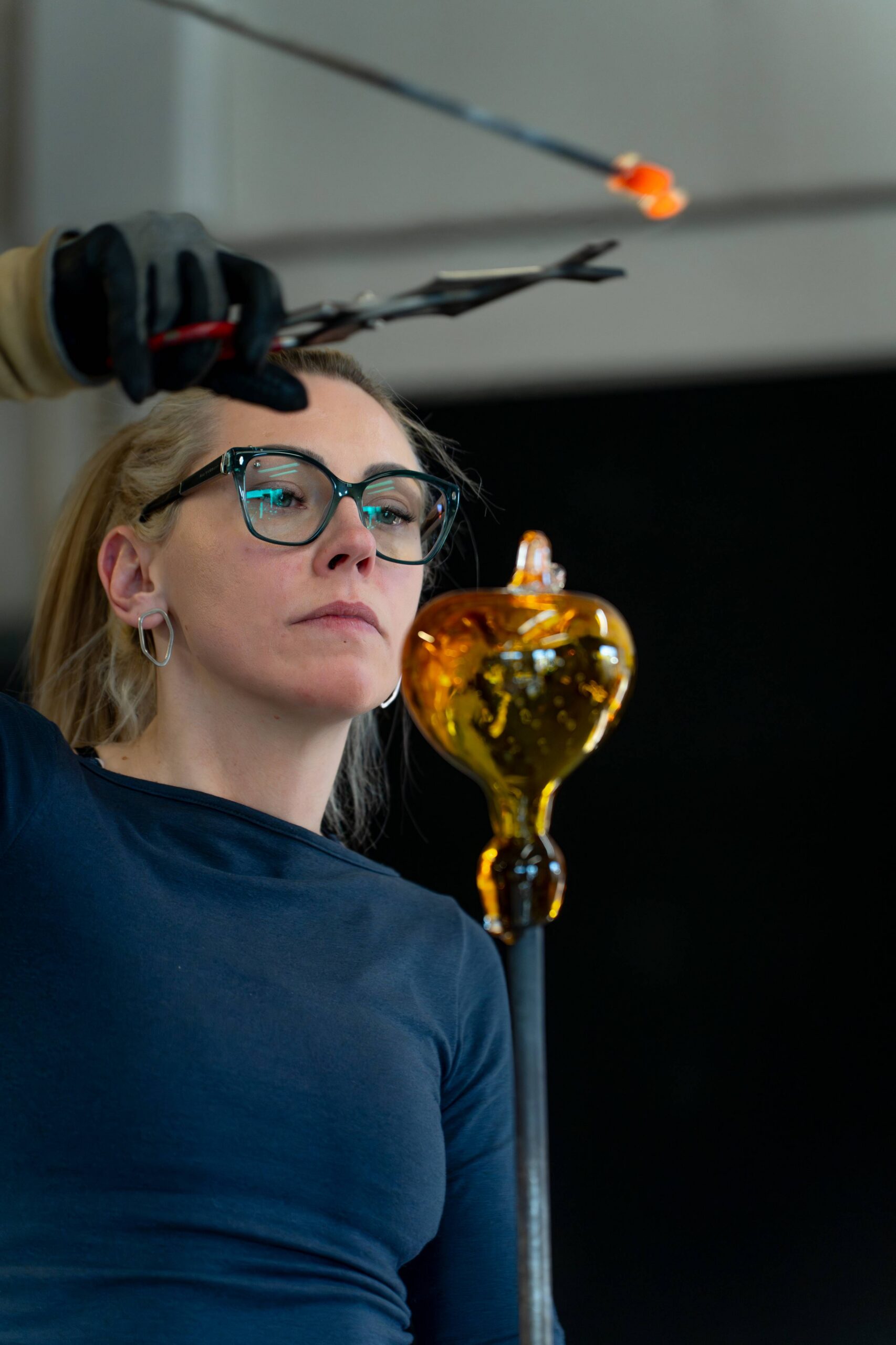Adding hot glass legs to the flycatcher, a moment before cutting the glass with shears.